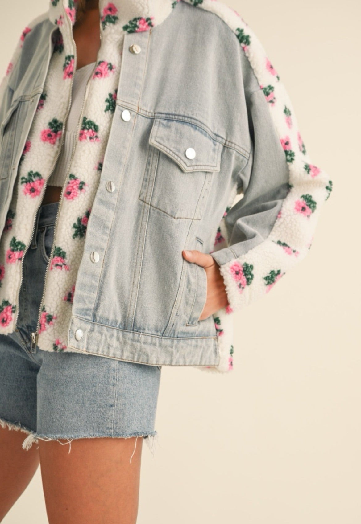 Denim jacket with floral pattern over a floral shirt on a neutral background